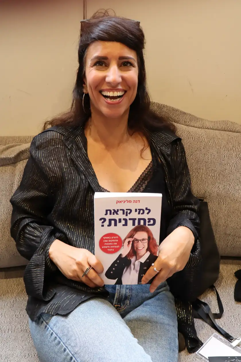 קוראת מחזיקה את הספר למי קראת פחדנית
