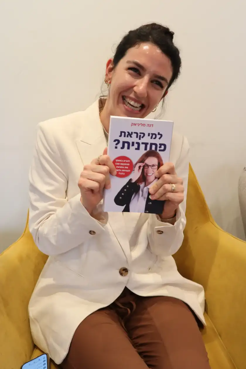 קוראת מחזיקה את הספר למי קראת פחדנית